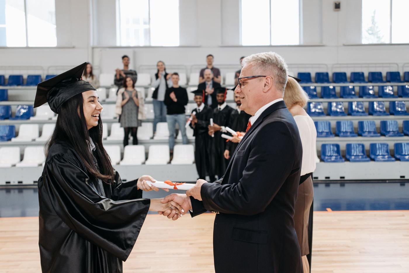 Graduada recibiendo diploma con toga y birrete
